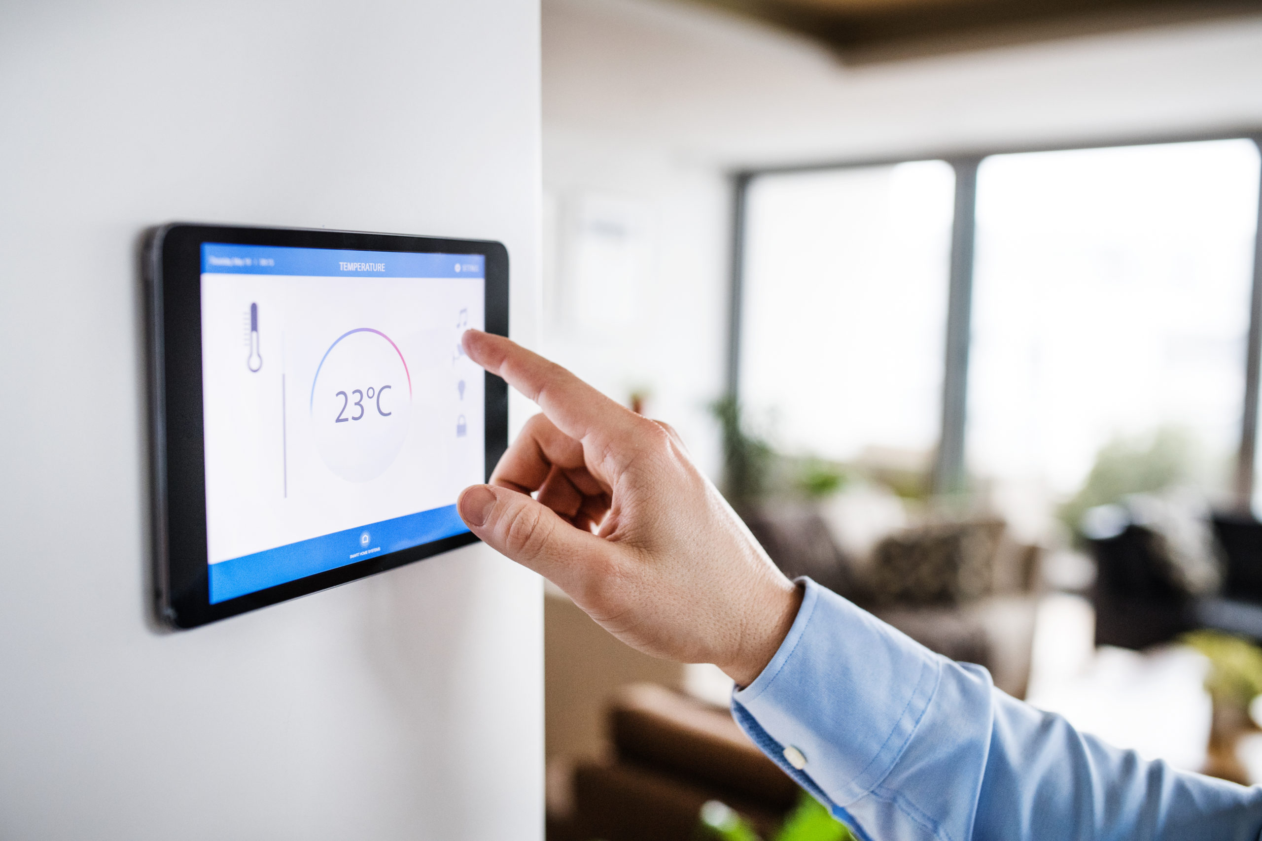 A man pointing to a tablet with smart home screen. An unrecognizable man pointing to a tablet with smart home control system.